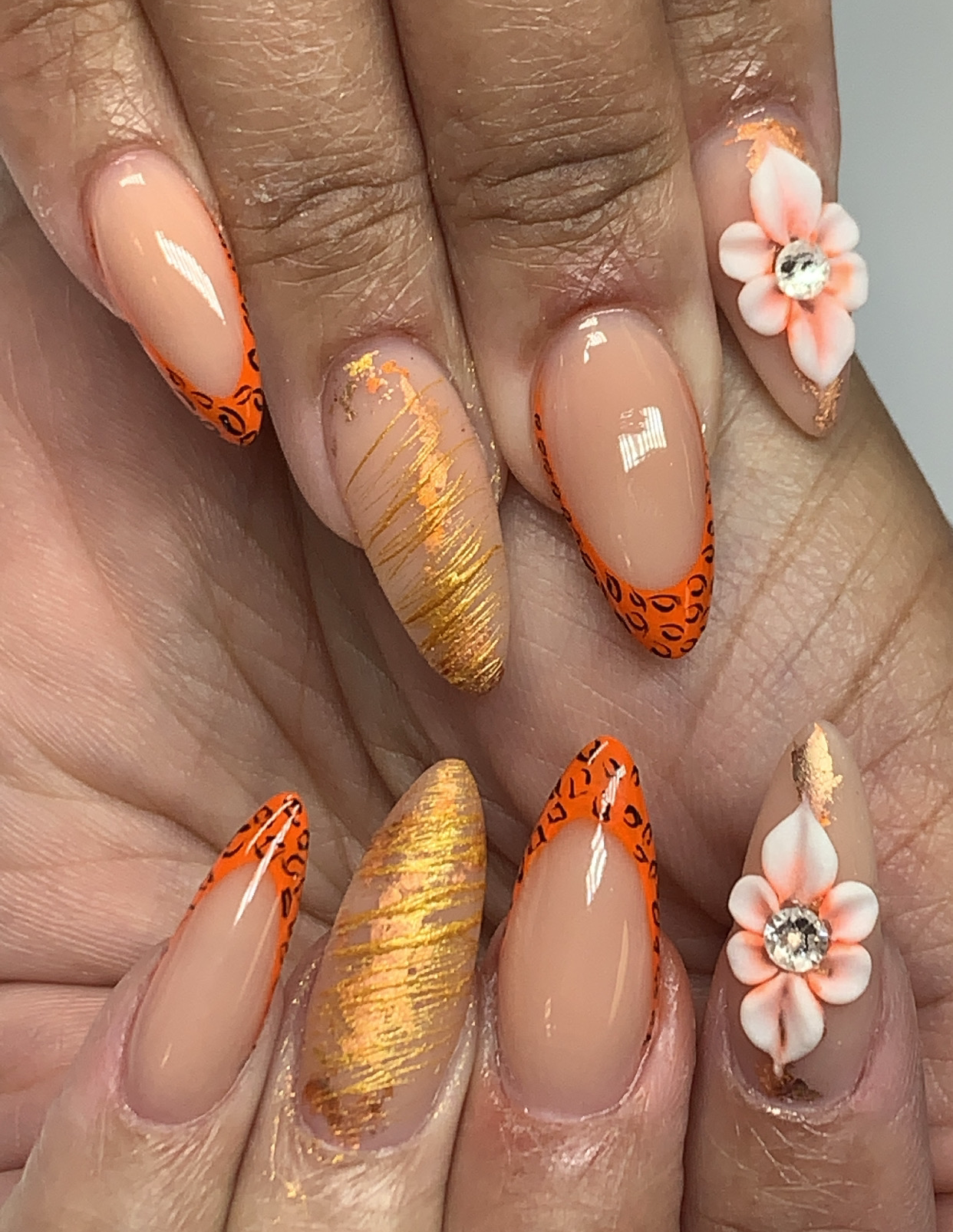 Neon-orange French tips with gold foil and 3D floral accents