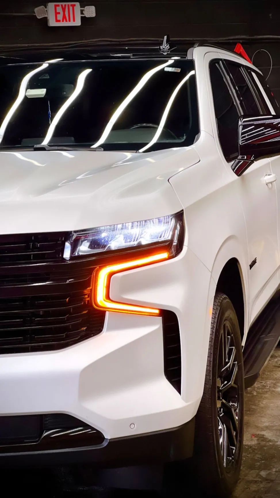 White full-size SUV under overhead LED detail-bay lighting